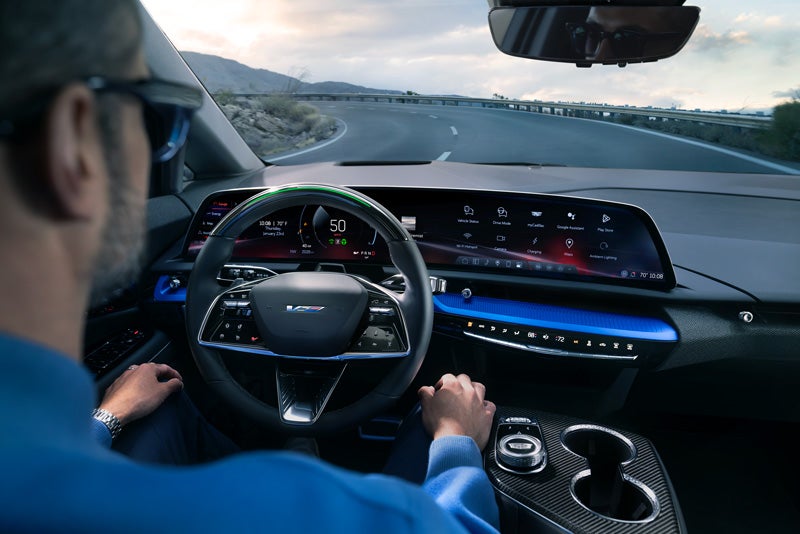 Front View of the 2026 OPTIQ-V Driving Through the Dusk Utilizing its Headlights | Fremont Cadillac in FREMONT CA